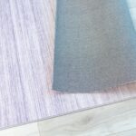 Rolled gray and purple area rug on floor