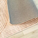 Patterned rug partially rolled on wooden floor.