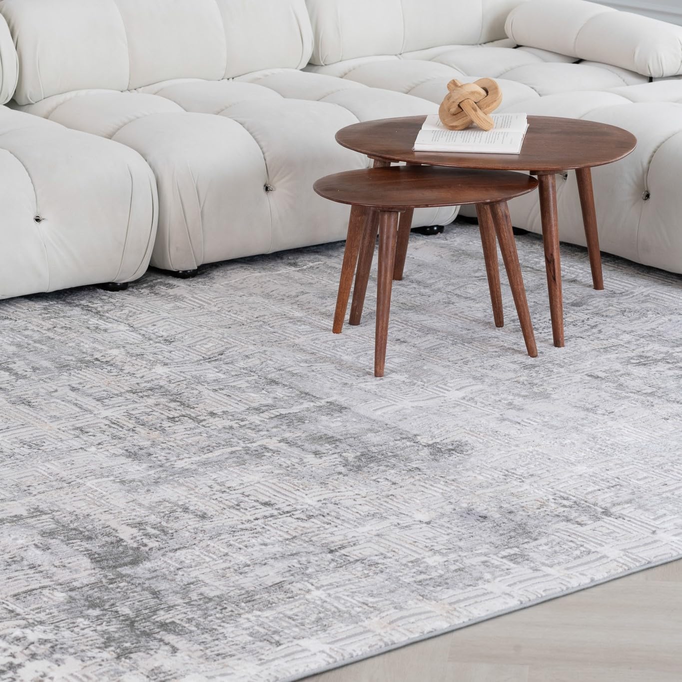 White sofa with round wooden tables and gray rug.