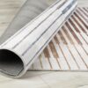 Rolled modern rug with striped pattern on floor.