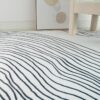 Black-and-white striped rug, minimal decor scene.