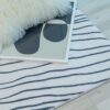 Fluffy pillow on striped blanket with art print.