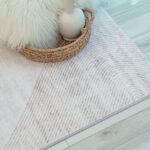 Neutral geometric rug on wooden floor.