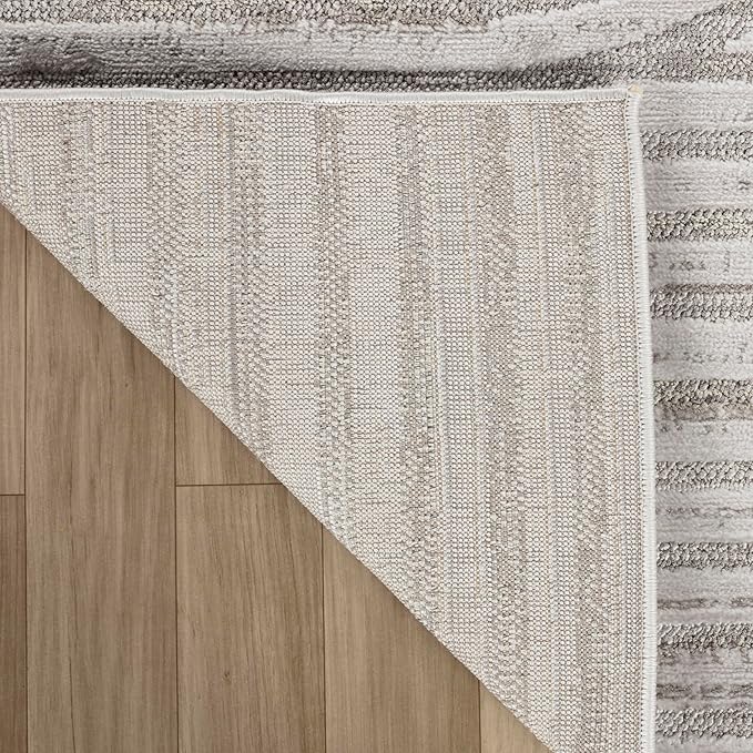 Textured beige rug corner on wooden floor.