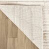 Beige area rug corner flipped on wood floor