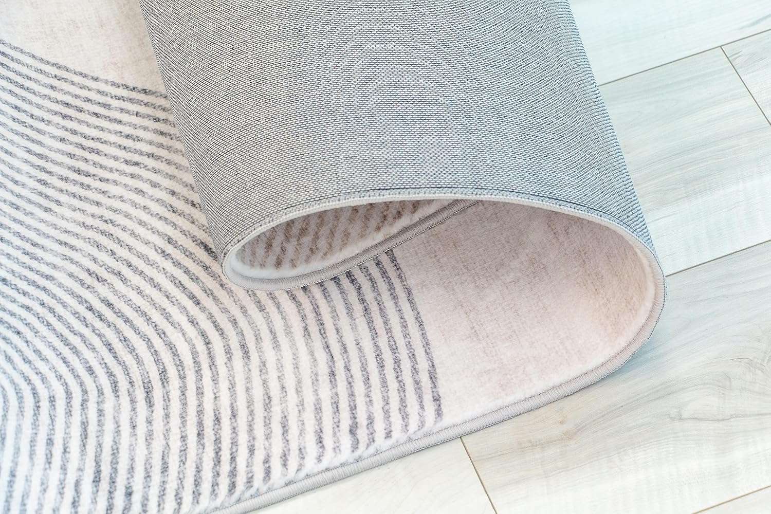 Rolled gray and white striped rug on floor