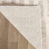 Corner of a rug folded on wooden floor.