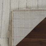 Corner of beige textured rug on wooden floor