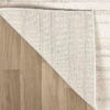 Corner of beige rug on wood floor