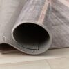 Rolled gray rug on wooden floor.