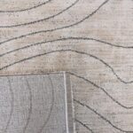 Beige rug with wavy gray lines, close-up view.