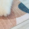 Abstract rug with fluffy white pillow on wood floor.