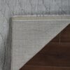 Gray rug corner flipped on wooden floor.