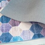 Hexagonal patterned rug with folded corner on floor.