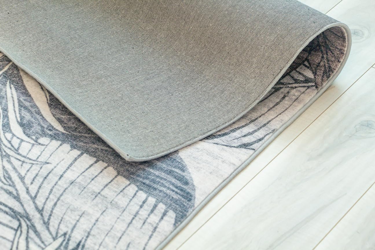 Folded gray and pattern rug on wooden floor.