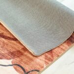 Rolled-up patterned carpet on wooden floor.