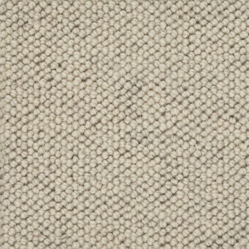 Beige textured wool carpet pattern close-up.