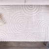 Modern geometric patterned beige rug on wooden floor.