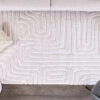 Beige rug with geometric pattern on wooden floor.
