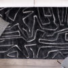 Black rug with abstract white lines on wood floor.