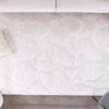 Beige textured rug with pillow and chair on floor.