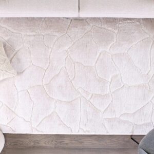 Beige textured rug with pillow and chair on floor.