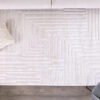 Modern beige rug with geometric pattern on hardwood floor.