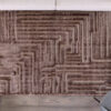 Geometric patterned brown rug on wooden floor.