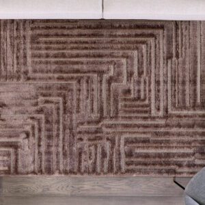 Geometric patterned brown rug on wooden floor.