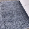 Gray patterned rug on wood floor beside couch.