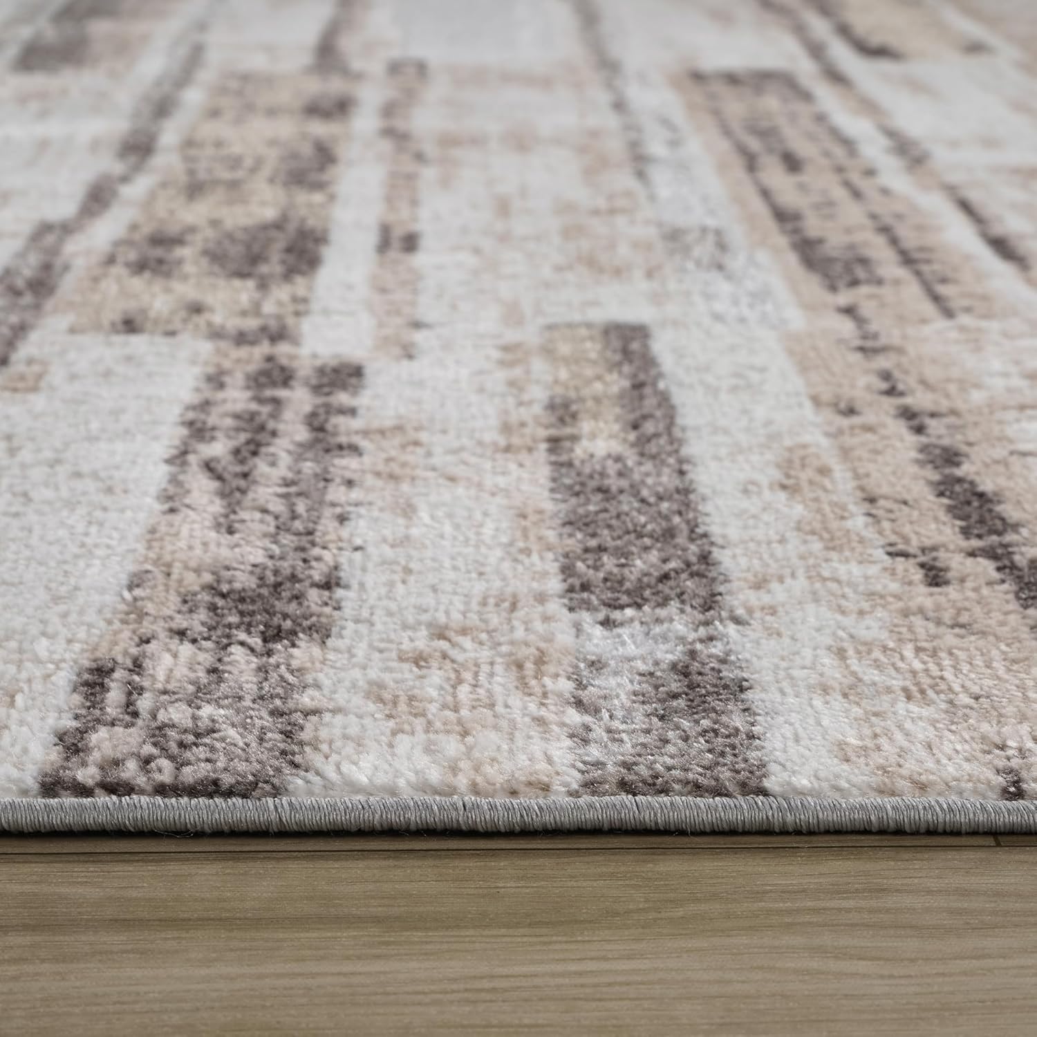 Textured beige and gray area rug on wooden floor.