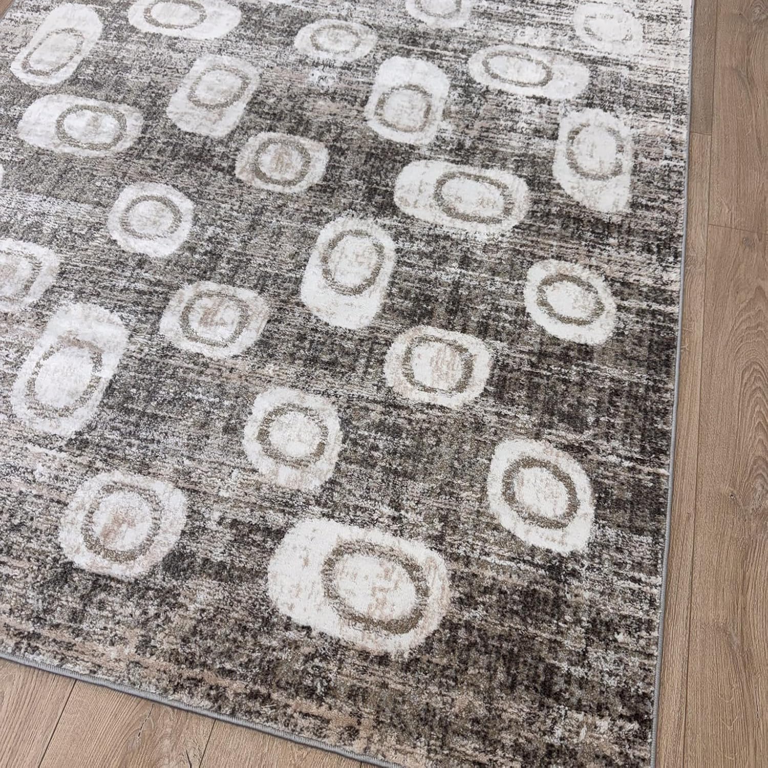 Gray rug with abstract circle pattern on wood floor.